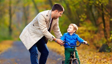 Parent pushing child on bike