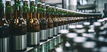Image shows rows of glass bottles containing beer. They are on a piece of machinery used to bottle beers from breweries